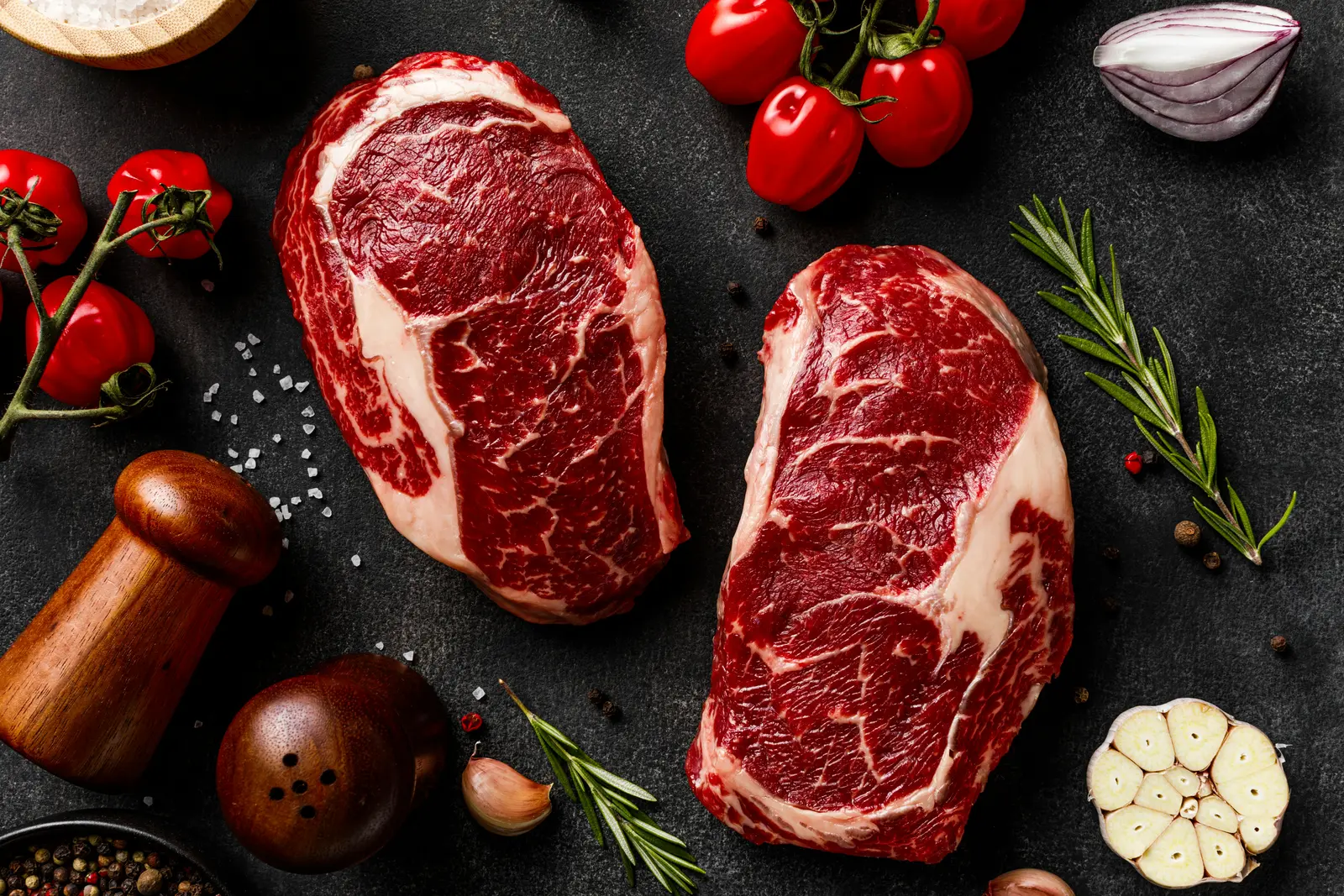 Two marbled beef steaks with fresh herbs and vegetables