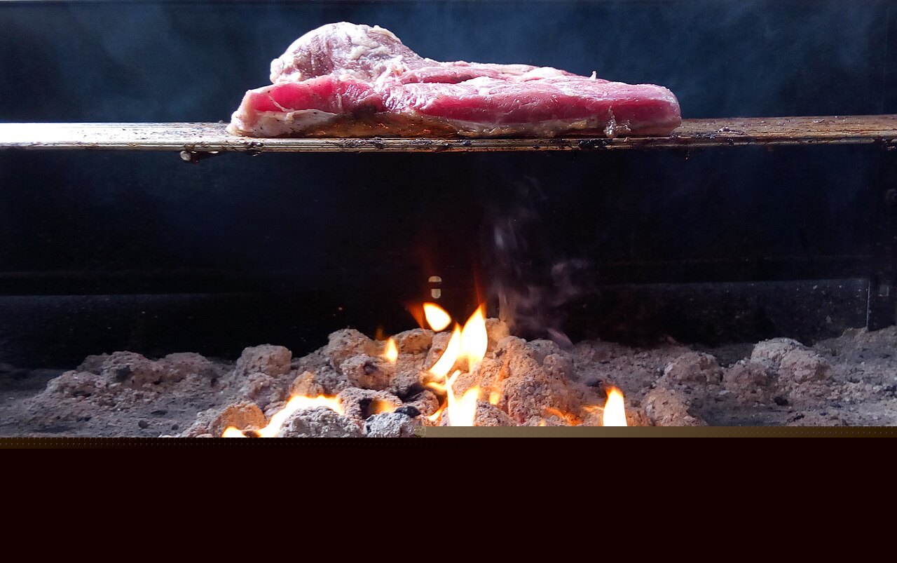 Steak grilling over charcoal