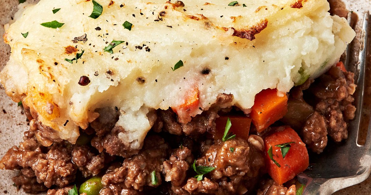 Shepherd's pie showing layers of mashed potatoes, ground beef, carrots, and peas